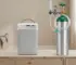 Oxygen concentrator machine next to an oxygen tank cylinder in a home setting